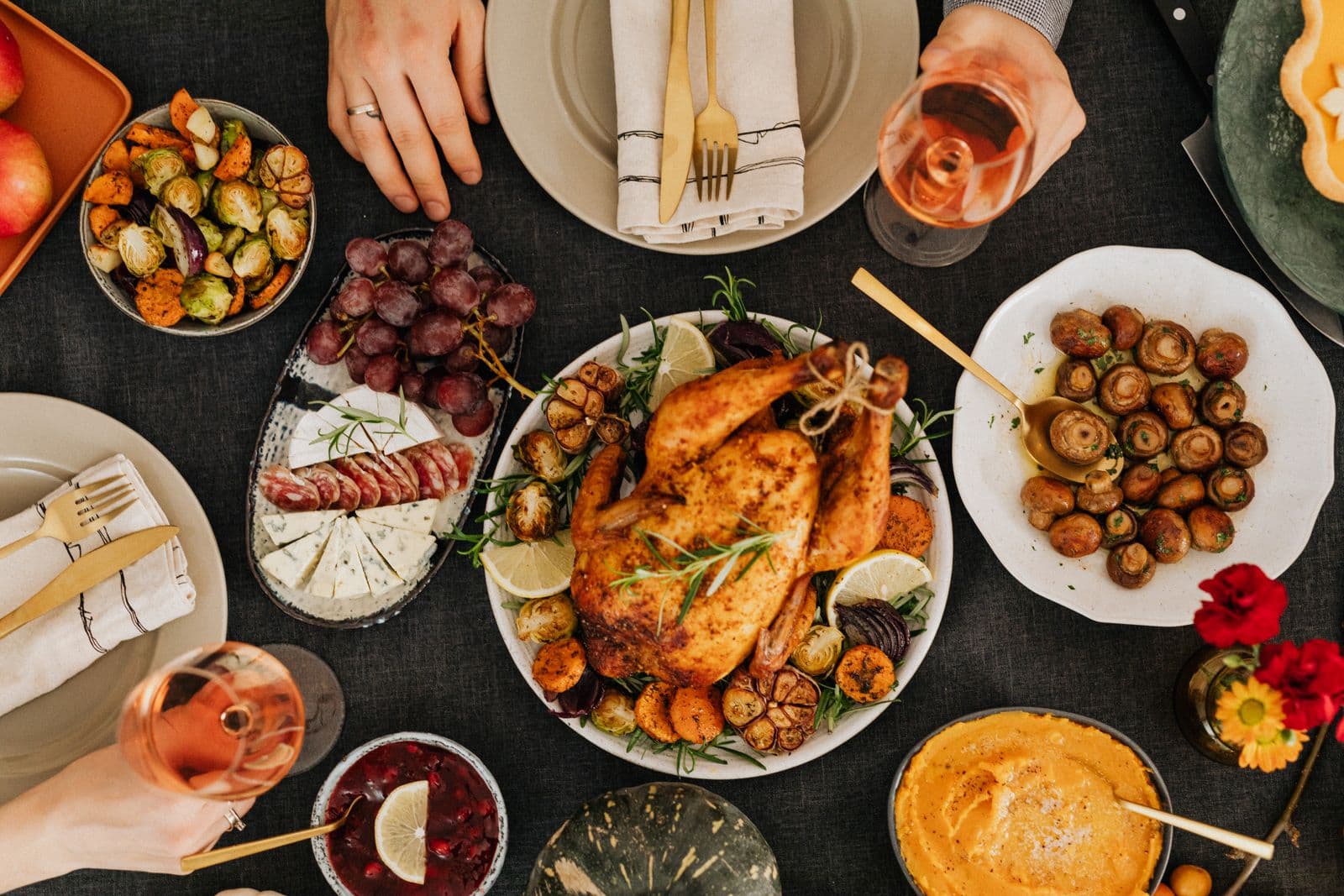 A loaded holiday table from above: roast turkey, Brussels sprouts, mushrooms, yams and cranberry