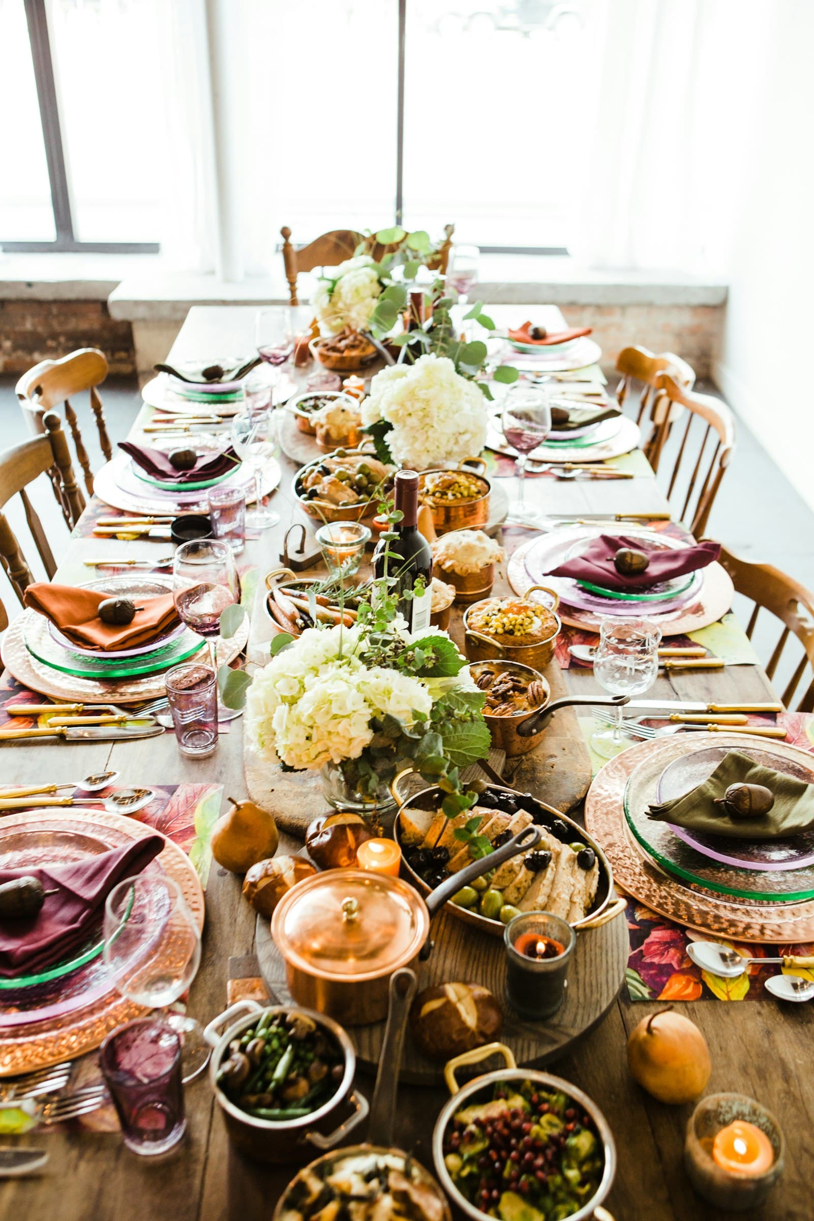 A long banquet table set for a crowd, filled with dishes, flowers and candles