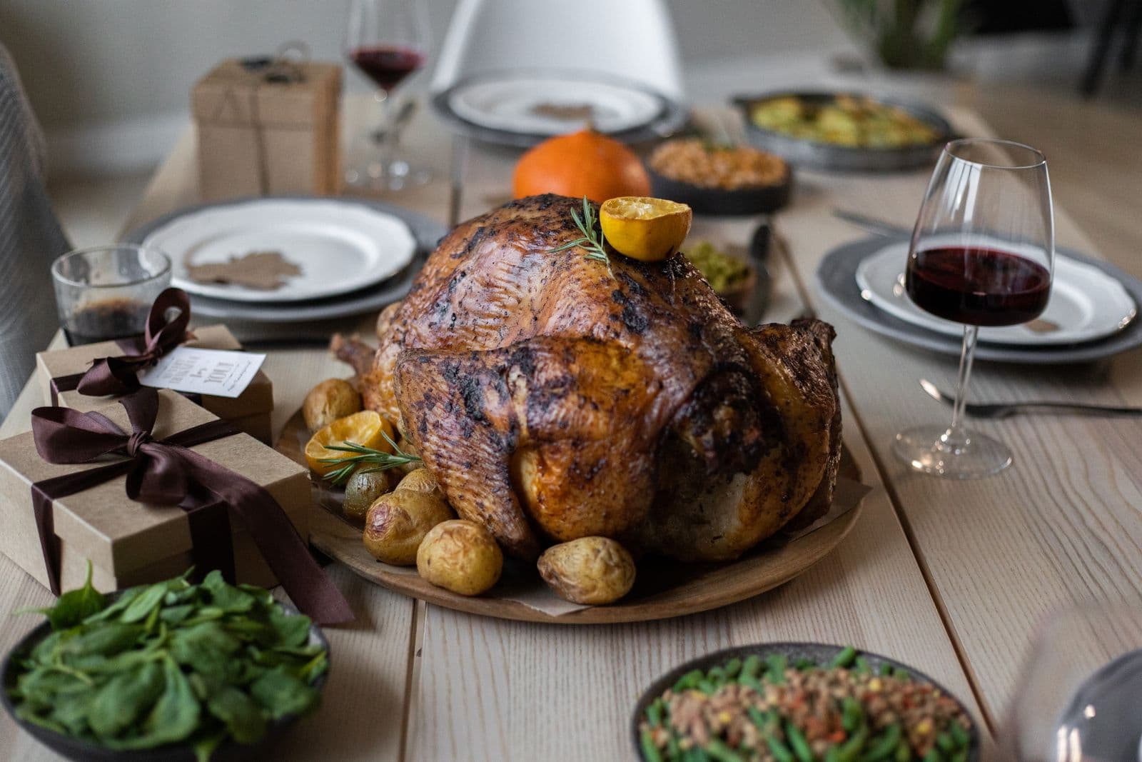 A whole roast turkey with potatoes at the centre of a set holiday table